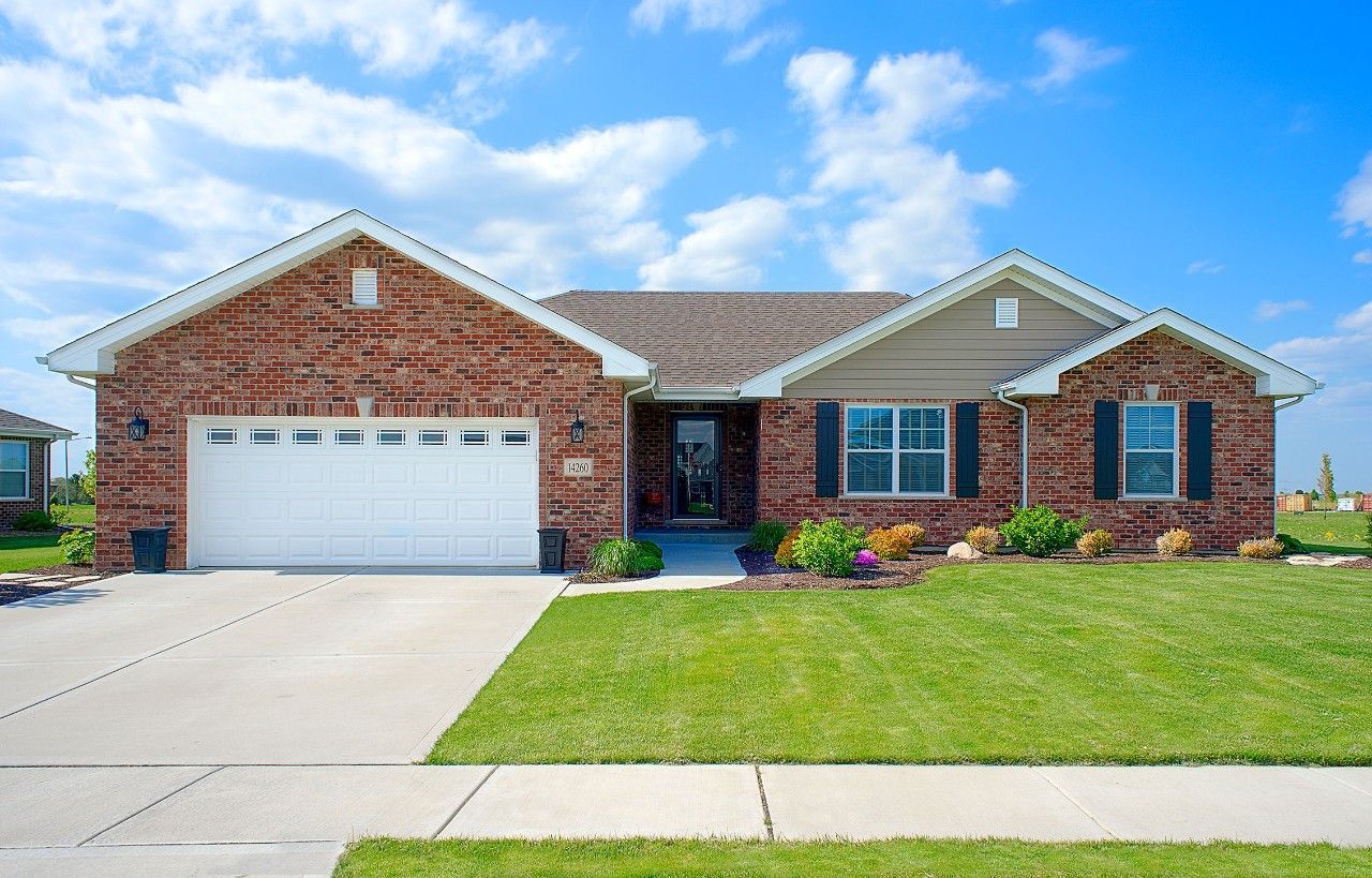 A large brick house with a white garage door and black shutters.