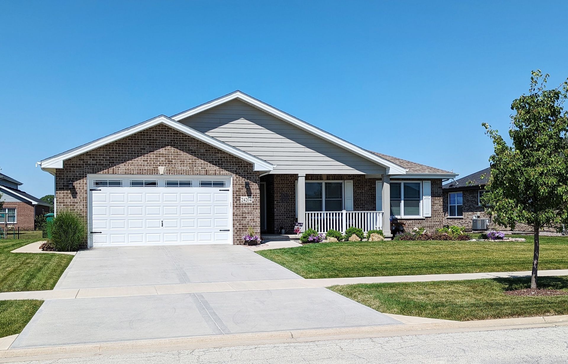 A house with a white garage door is sitting on top of a lush green lawn.