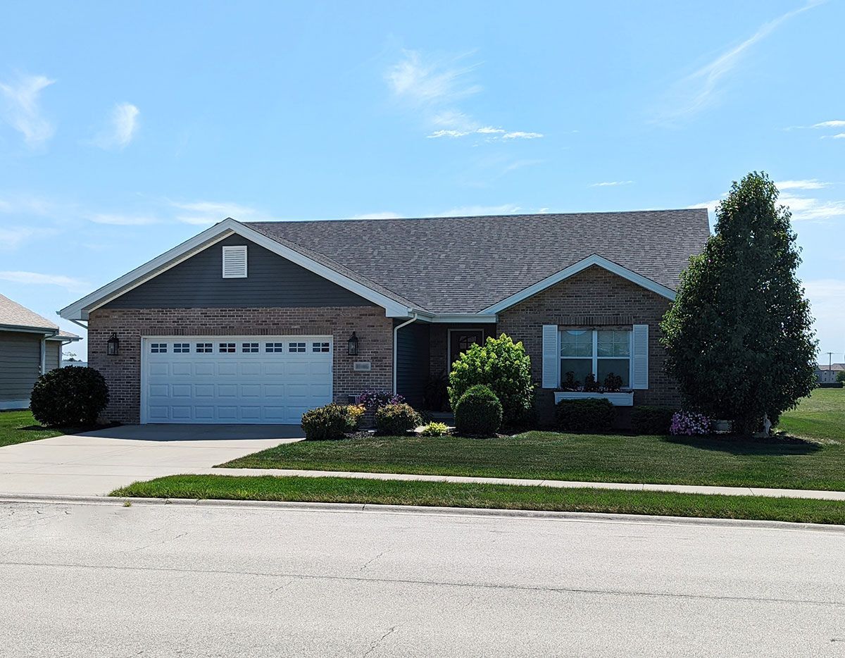 A brick house with a white garage door and a blue sky in the background.