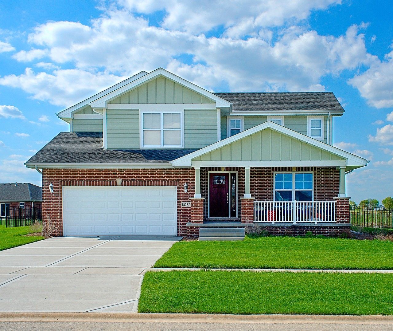 A brick house with a green siding and a white garage door