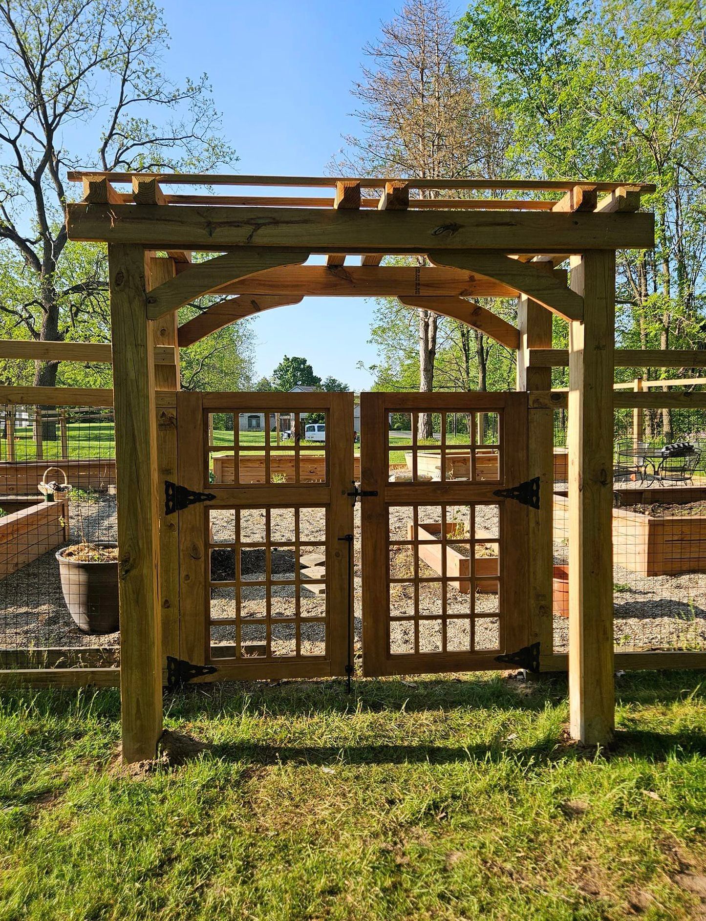 A wooden gate is surrounded by a fence in a garden.