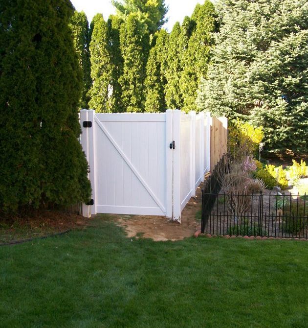 A white fence surrounds a lush green yard.