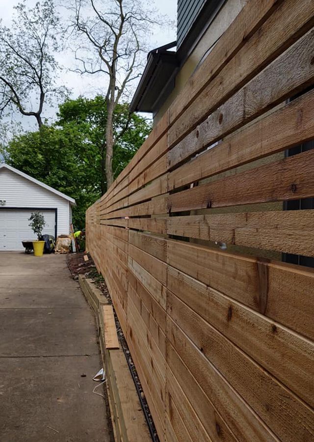 A wooden fence is being built in front of a house.