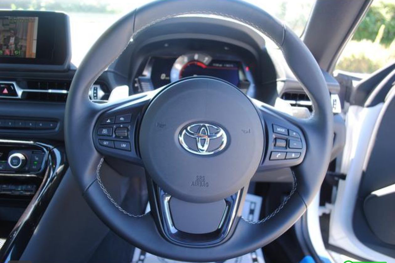 Black Toyota Supra steering wheel with control buttons and Toyota logo.