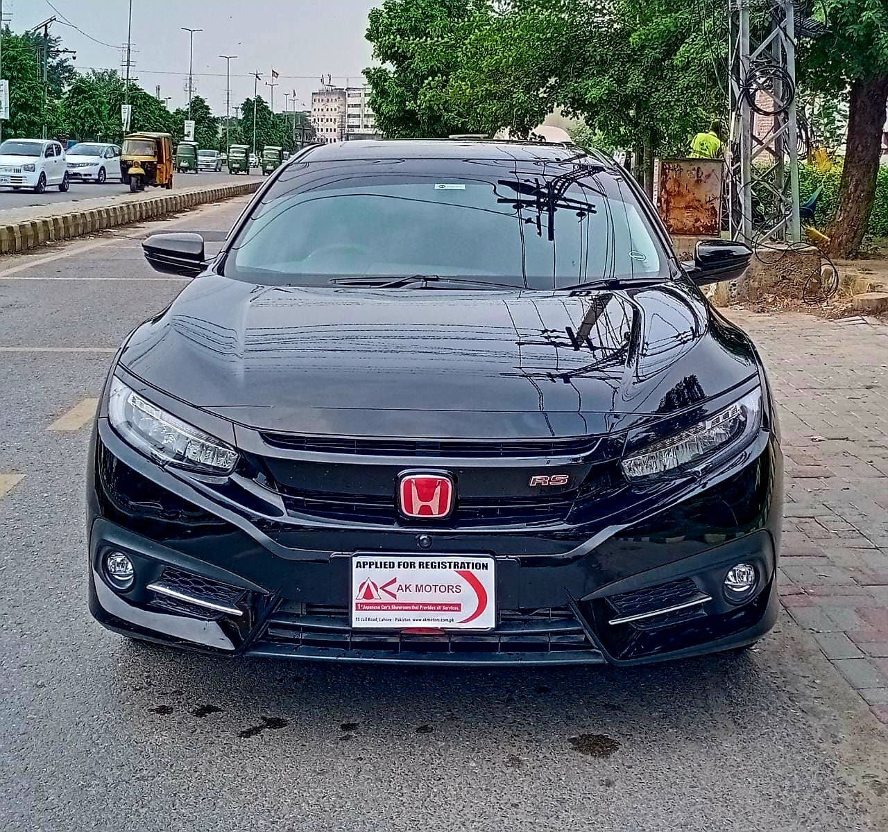 Black Honda Civic RS parked on a street with a red emblem and a license plate.
