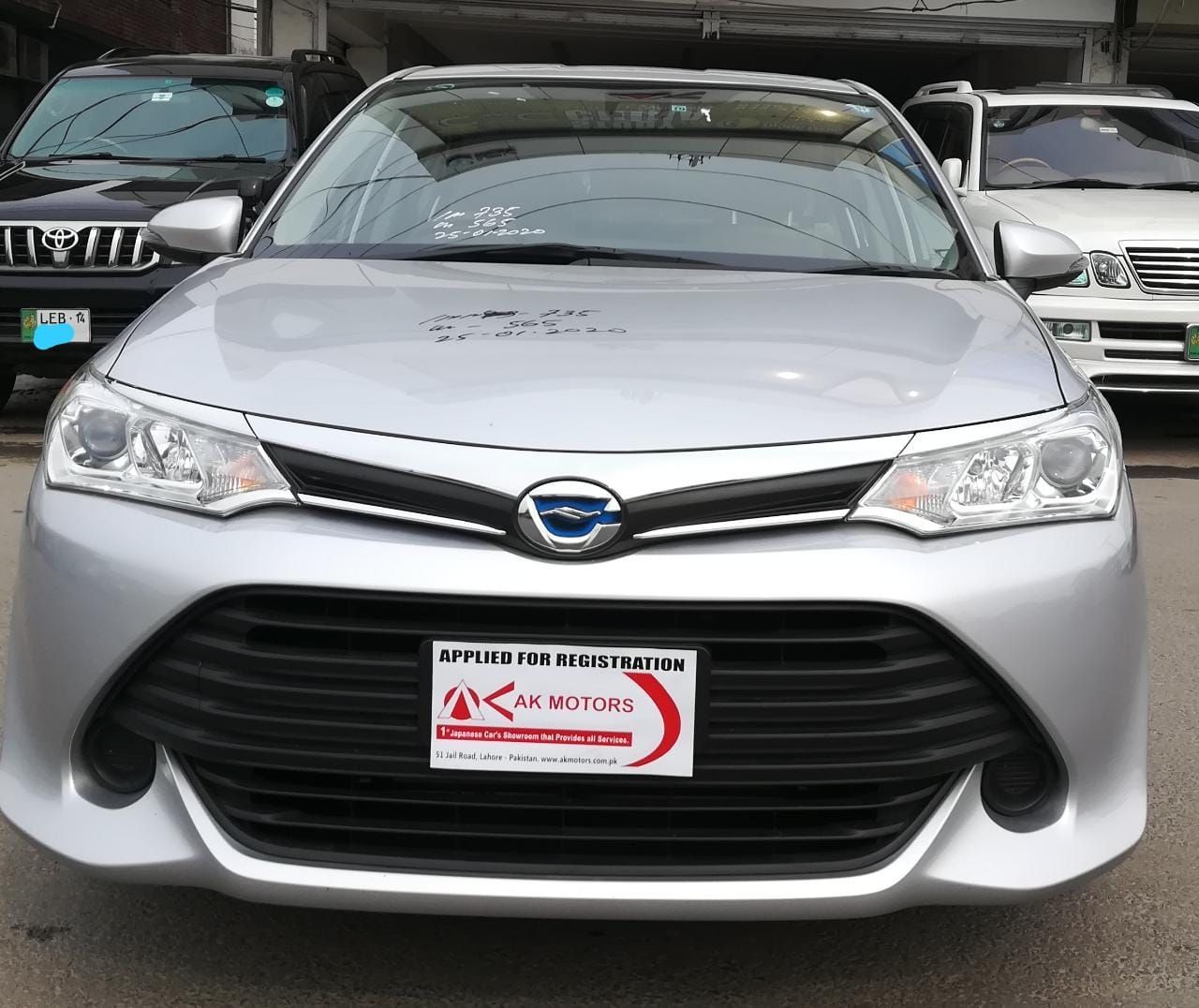 Silver Toyota Corolla hybrid car, front view, parked in front of a building.