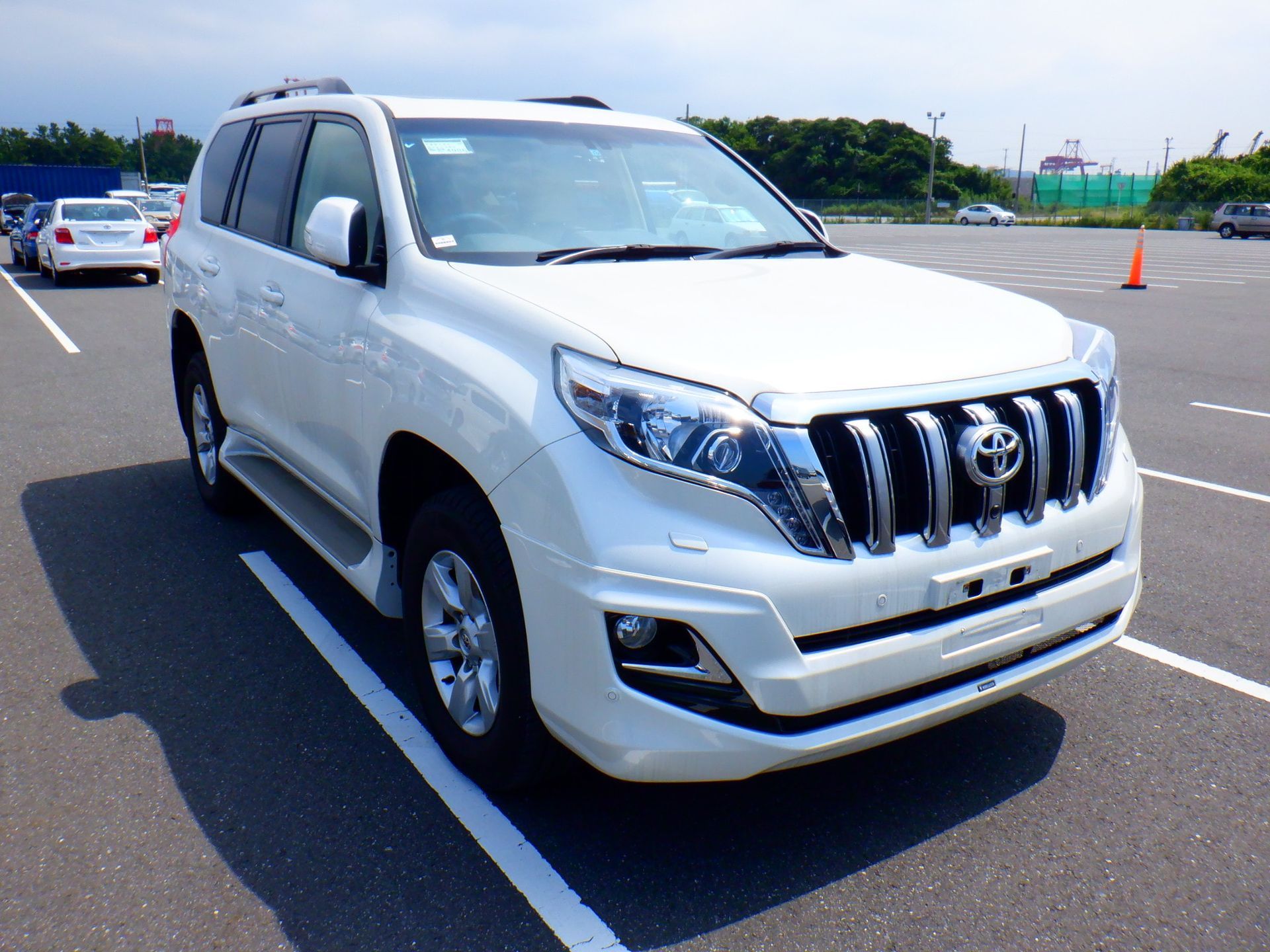 White Toyota Land Cruiser Prado parked in a parking lot on a sunny day.