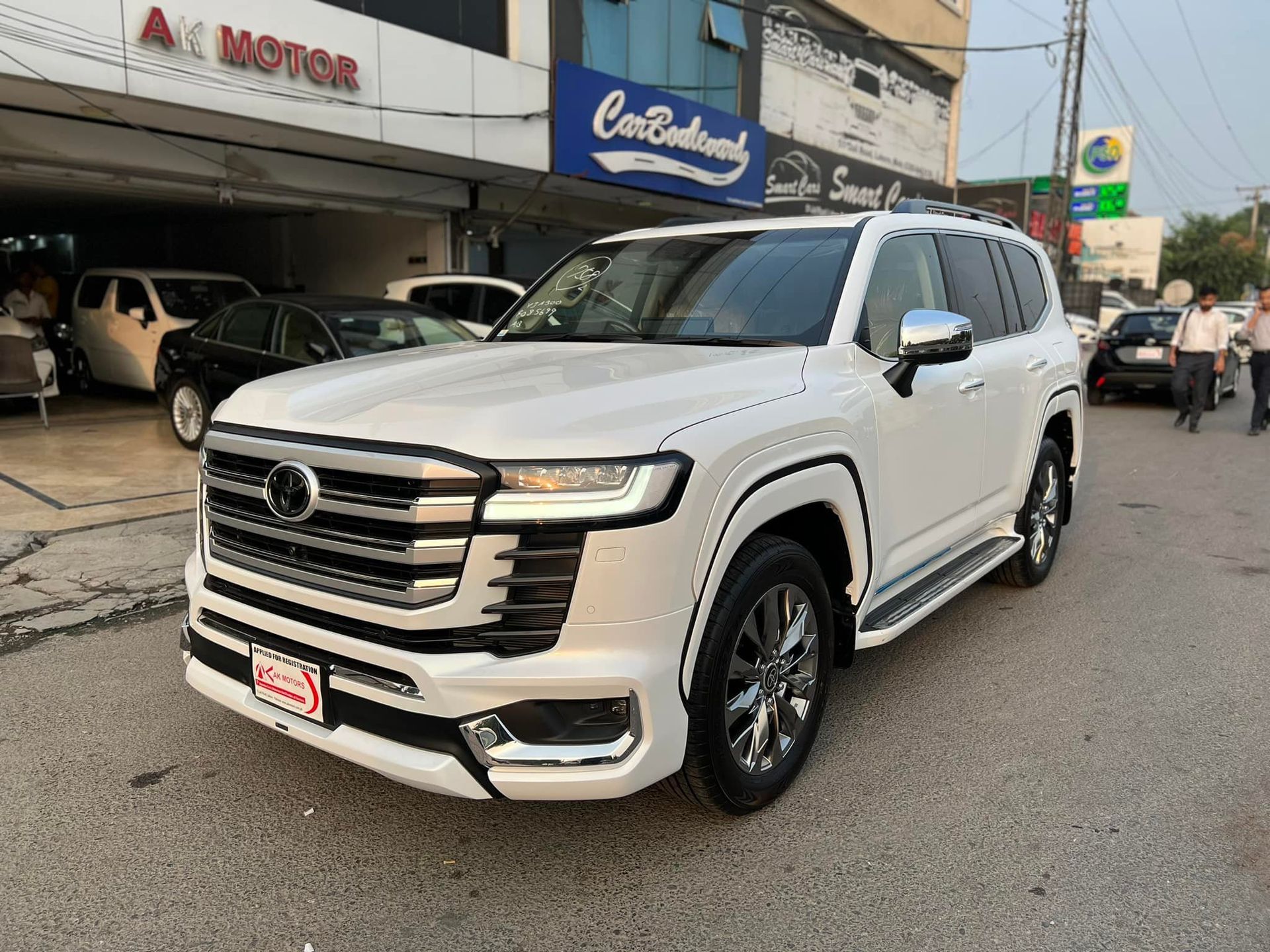 White Toyota Land Cruiser SUV parked in front of a car dealership.