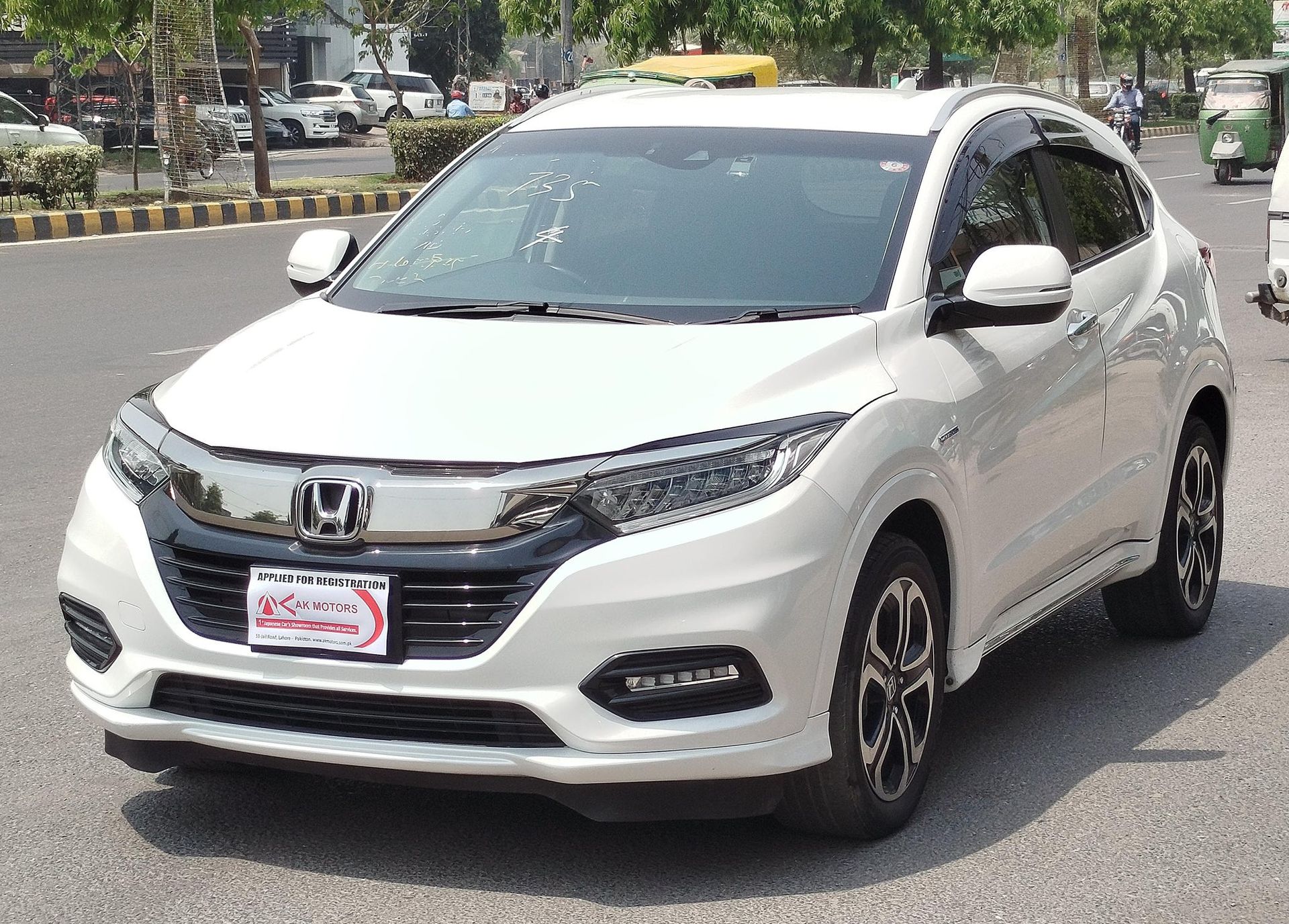 White Honda HR-V crossover SUV parked on a city street in front of a road median.