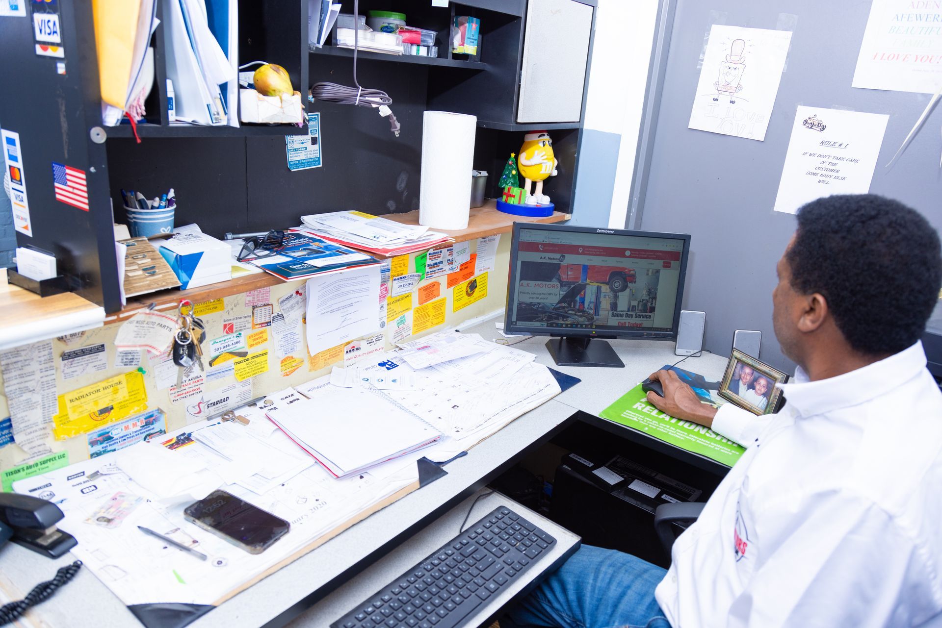 Person working at a cluttered desk with a computer and papers.