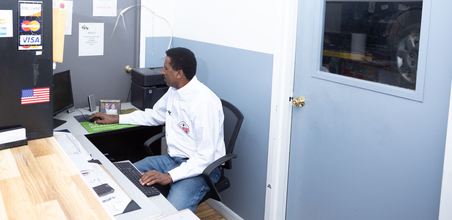 Man sitting at a desk, typing on a keyboard, in a small office space.