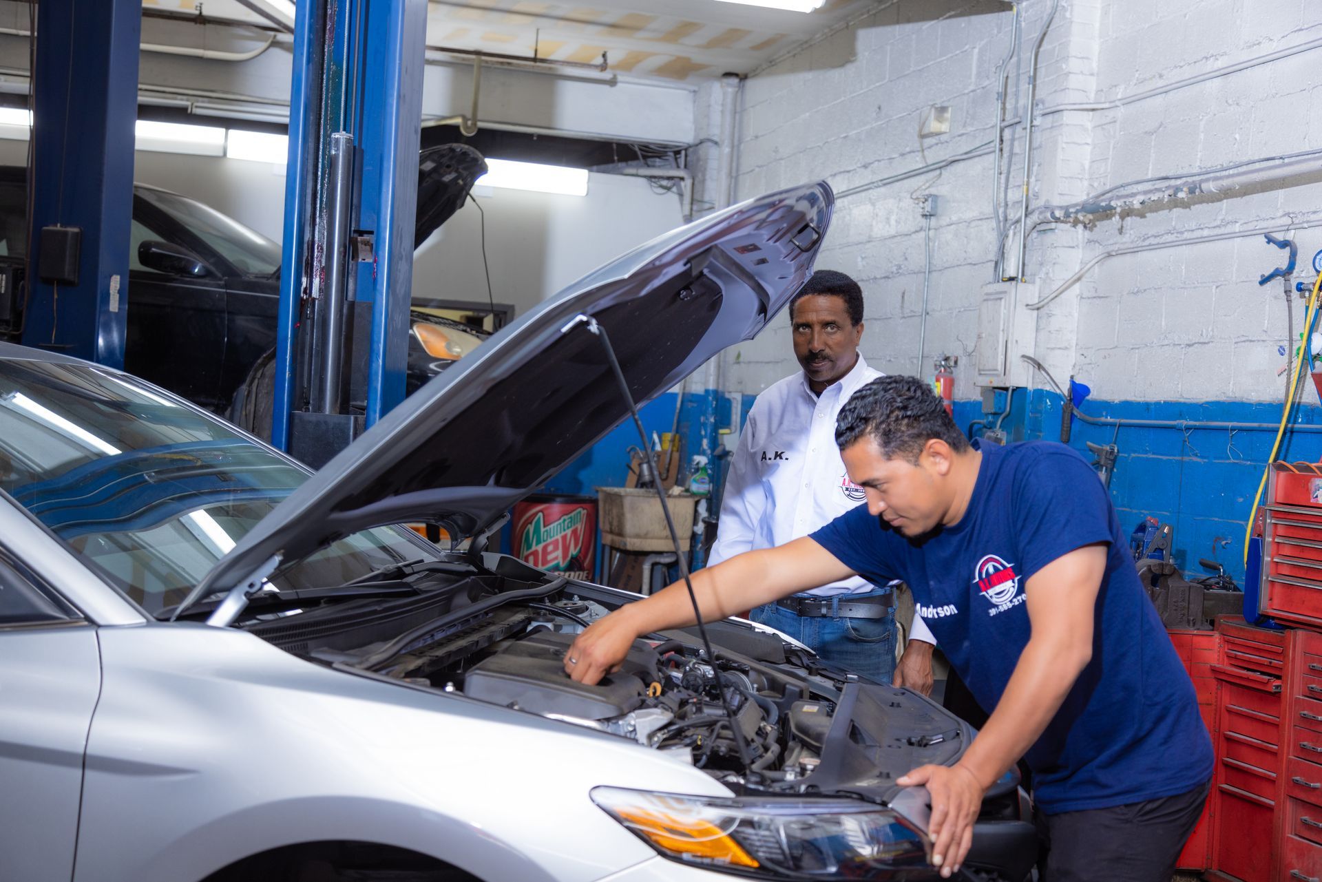 Two mechanics examining a car engine in a repair shop.