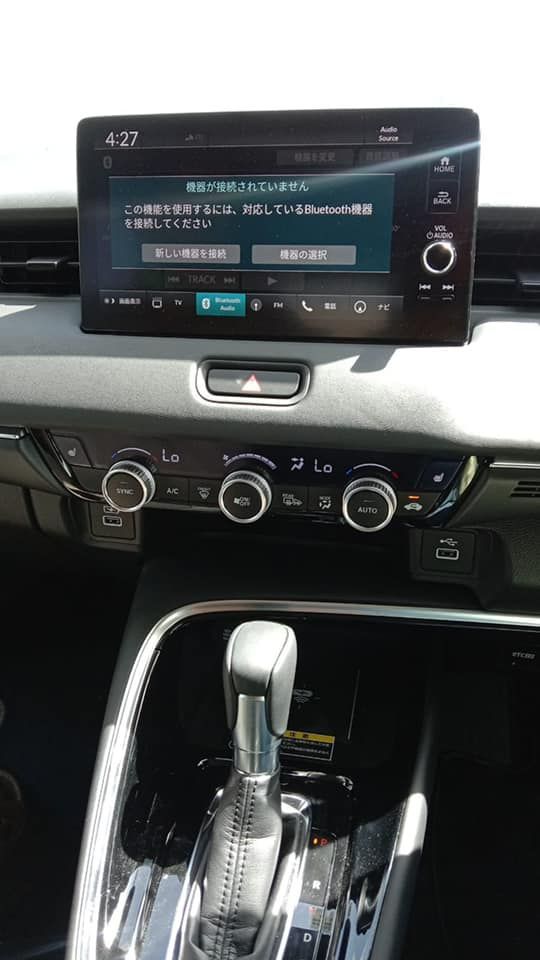 Dashboard of a car with a display screen showing Japanese text and controls. Automatic gear shift is visible.
