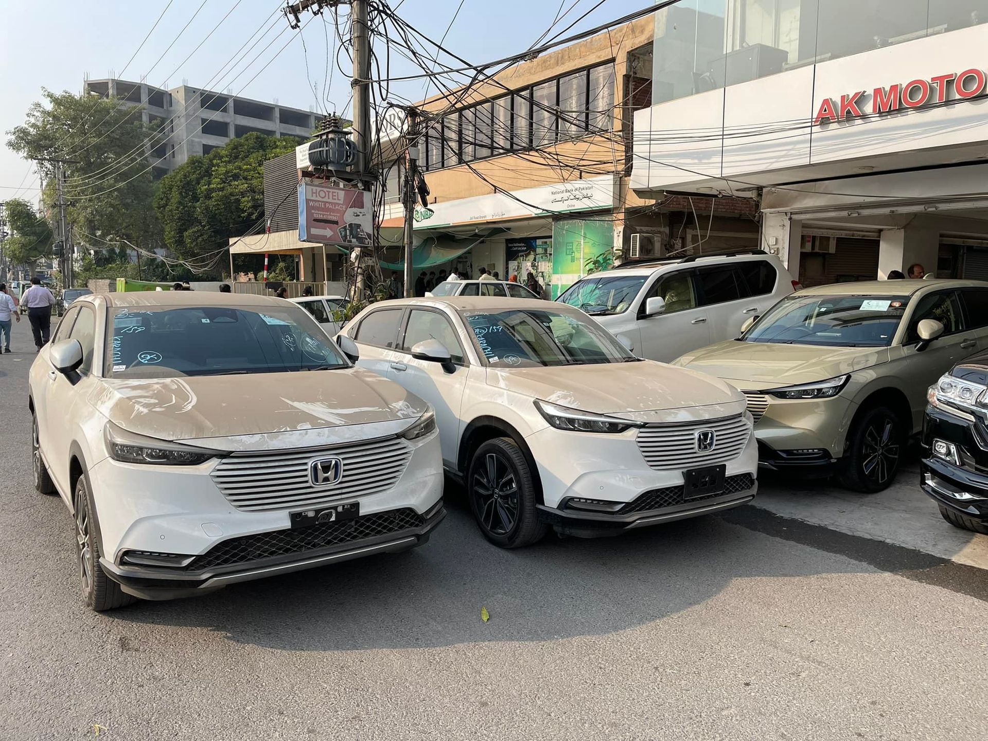 White Honda HR-V SUVs parked outside a building with signage. Sunny outdoor setting.