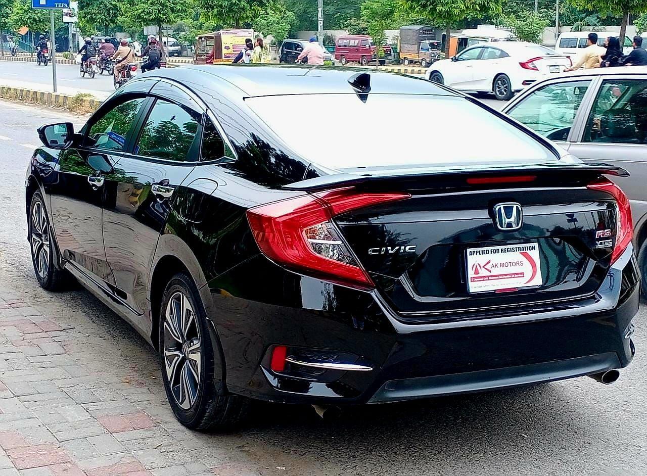 Black Honda Civic sedan parked on a city street, rear view.