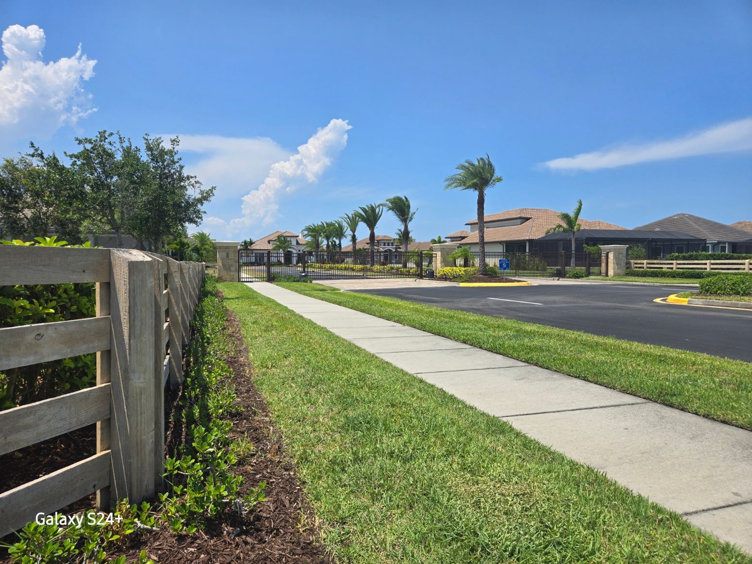 A wooden fence along a sidewalk in a residential area.