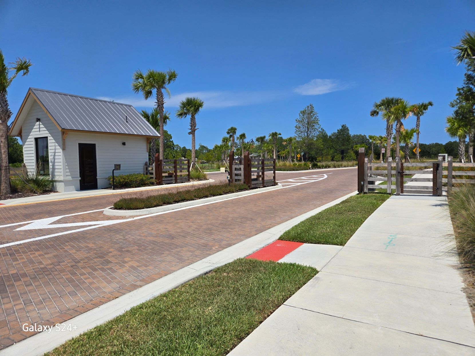 A small white building is sitting on the side of a road next to a sidewalk.