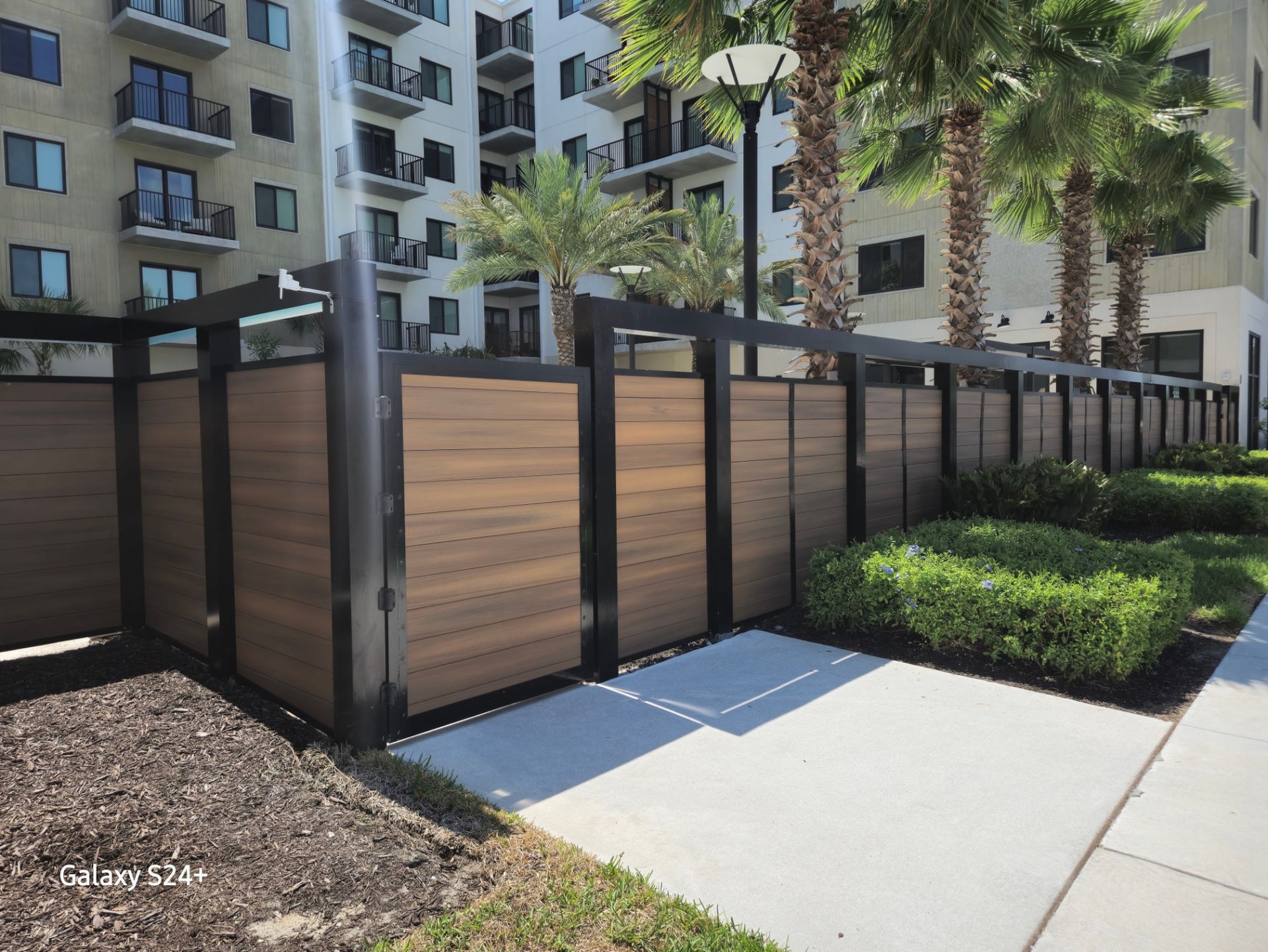 A wooden fence in front of a building with palm trees