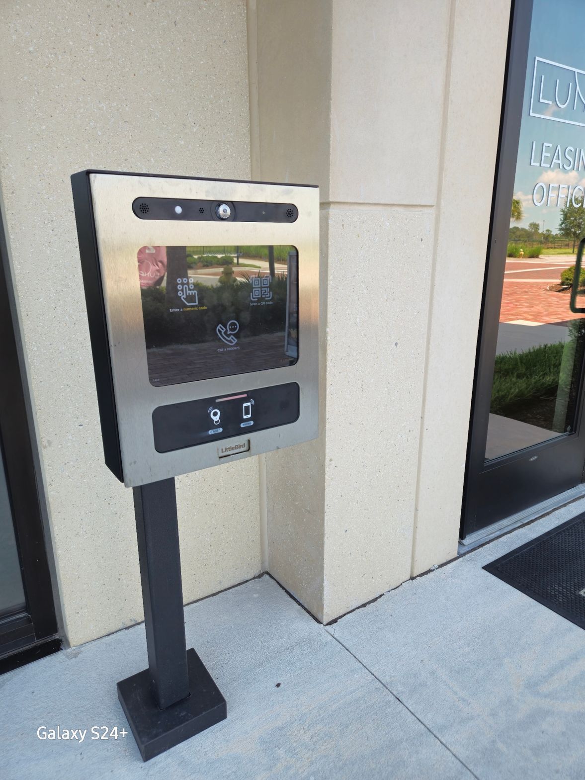 A stainless steel box is sitting on the sidewalk in front of a building.