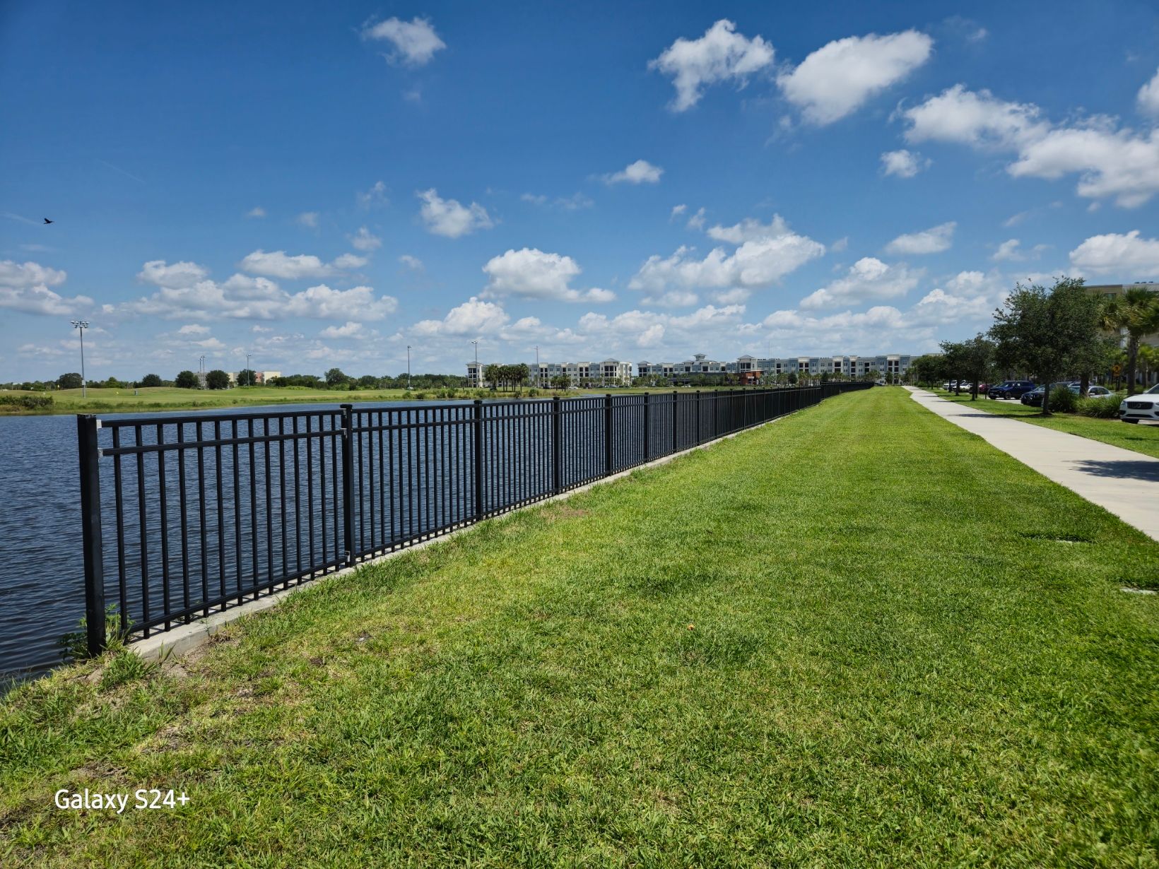 There is a fence along the side of a lake.