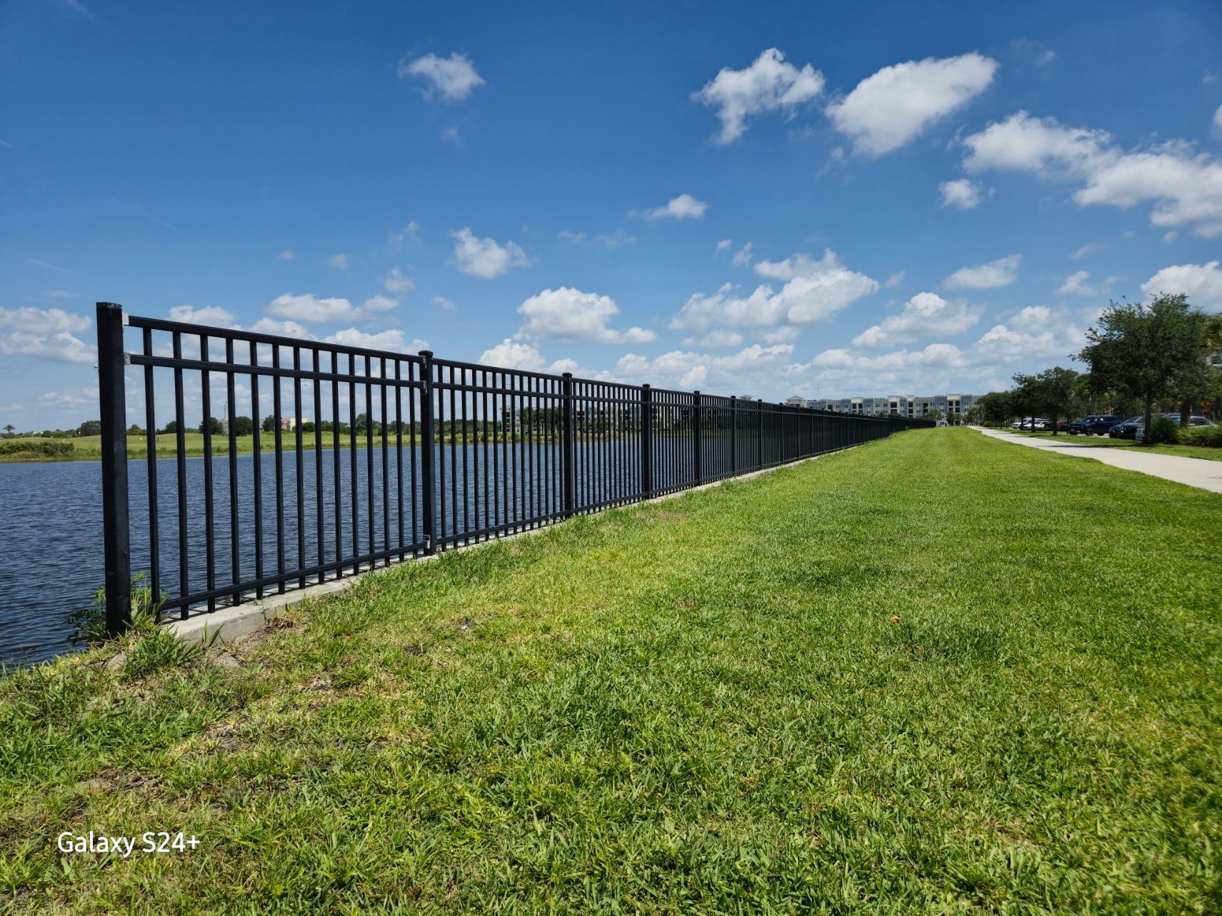 A black metal fence surrounds a body of water.