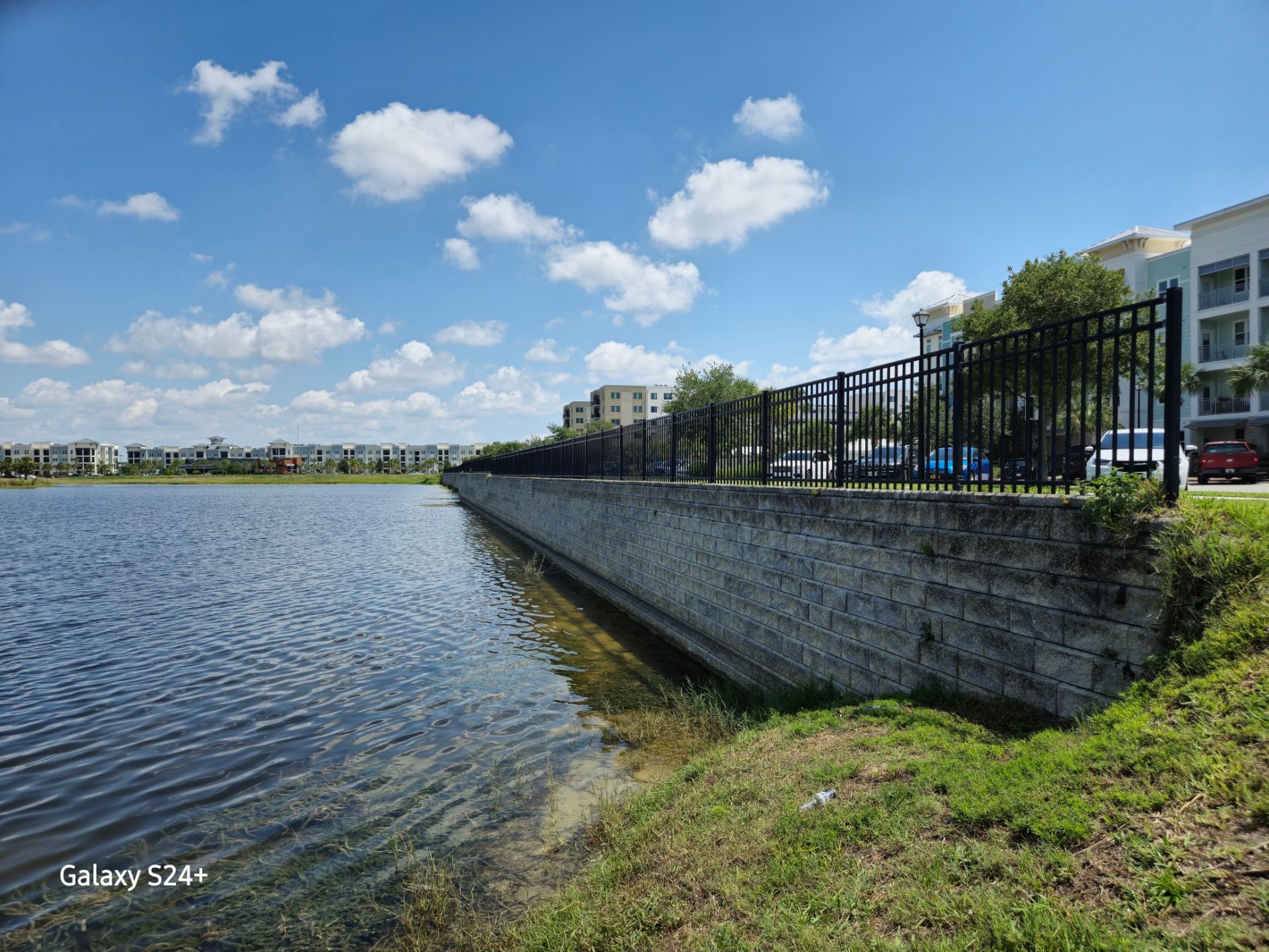 A large body of water surrounded by a fence and a brick wall.