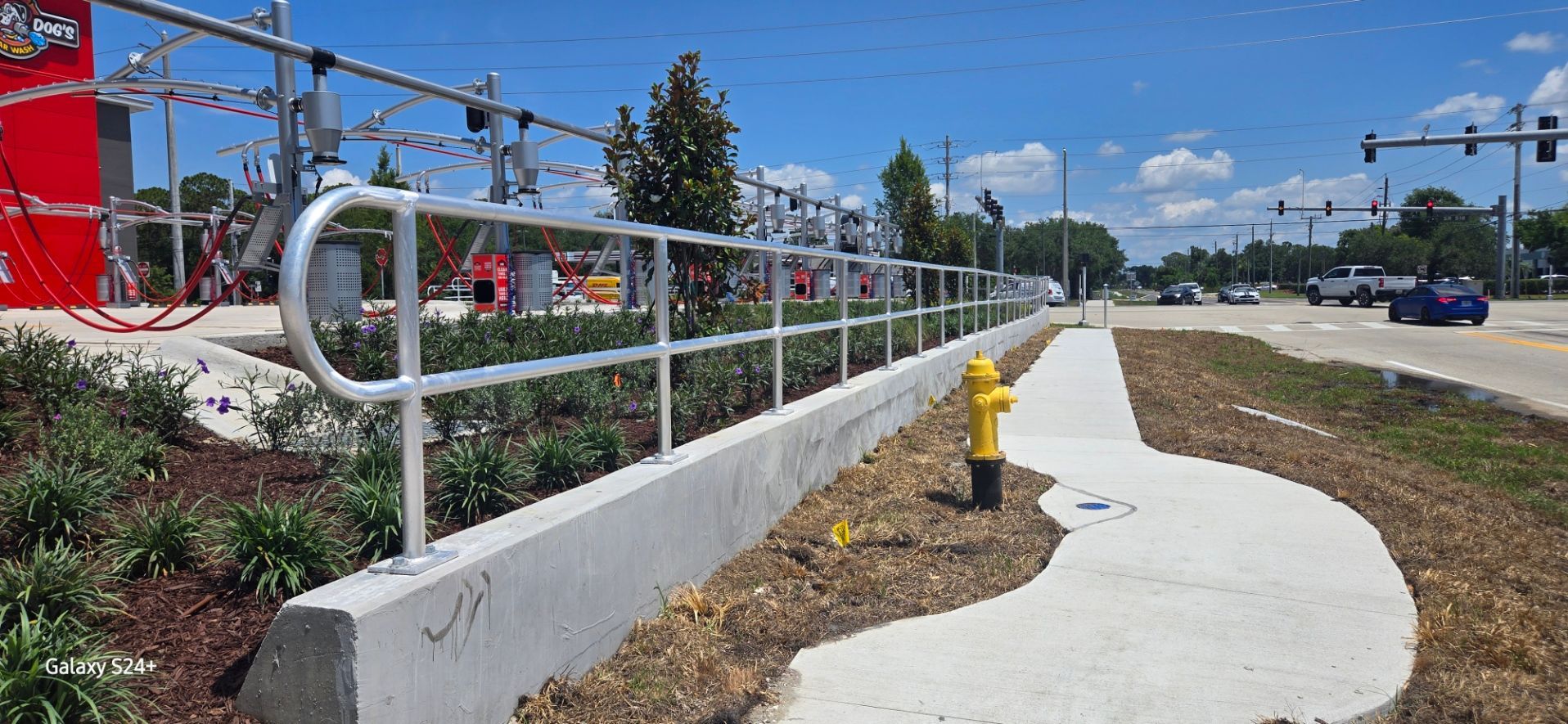 A fire hydrant is sitting on the side of a sidewalk next to a fence.