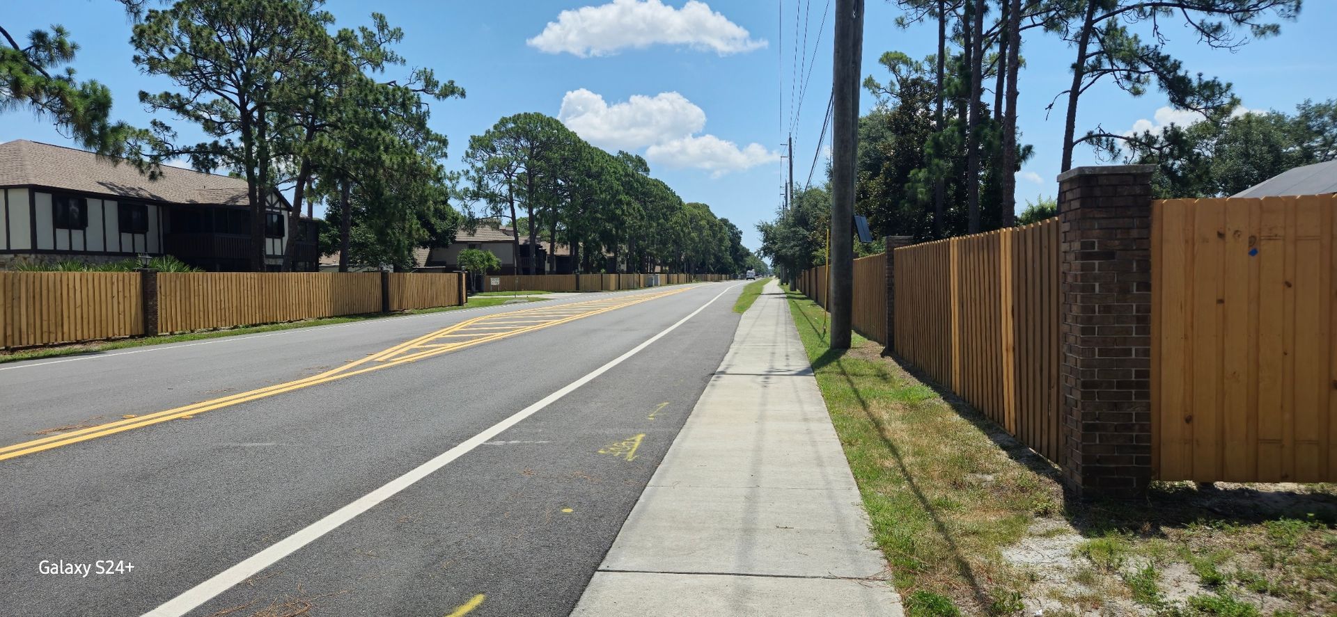 There is a wooden fence along the side of the road.