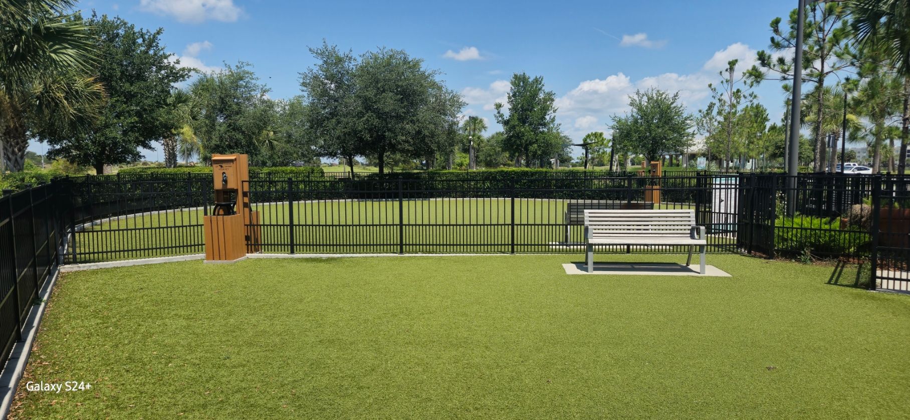 A park with a fence and a bench in the middle of it.