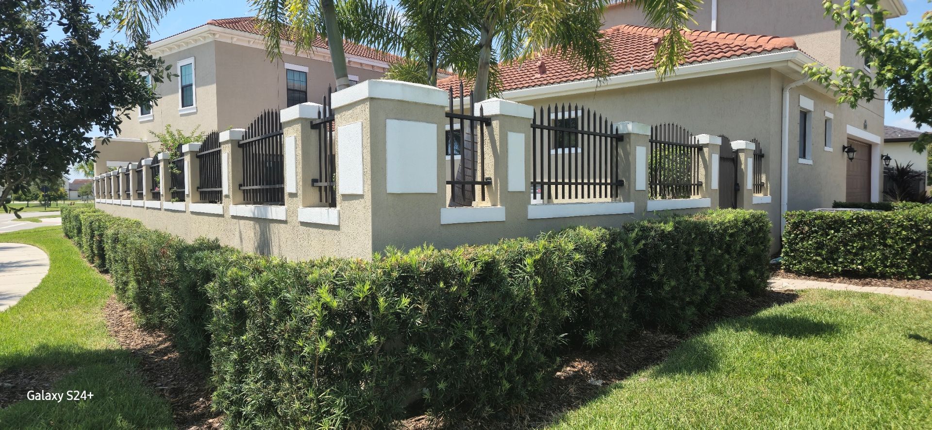 A house with a fence and bushes in front of it.