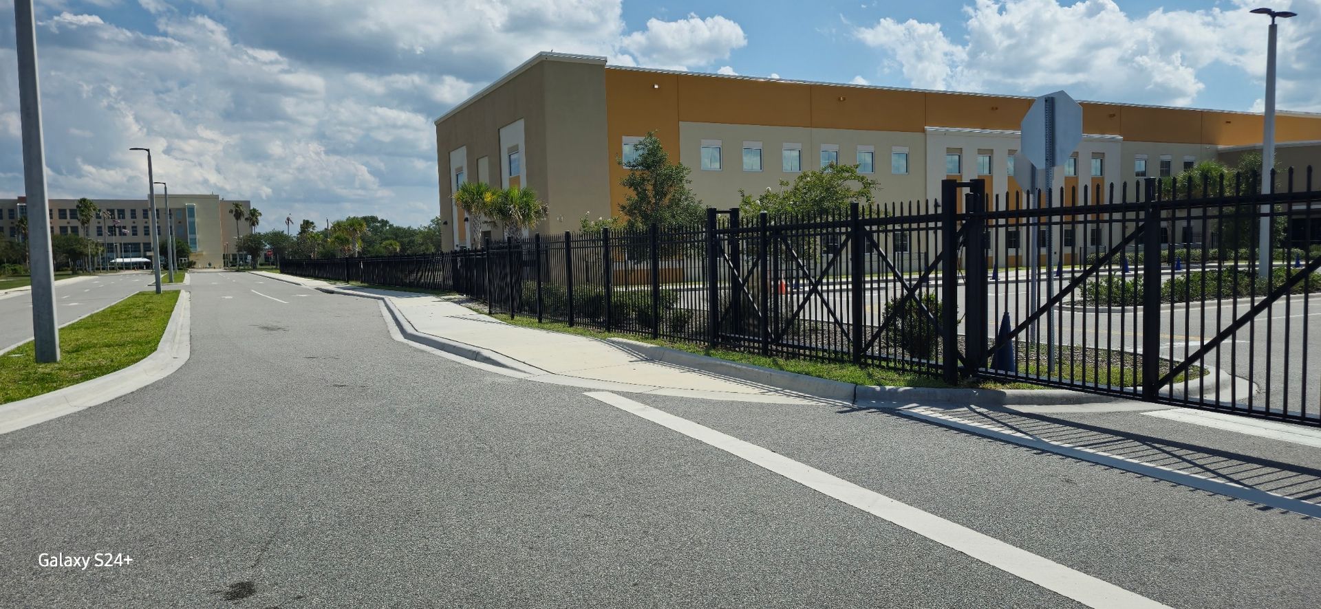 A road with a fence and a building in the background.