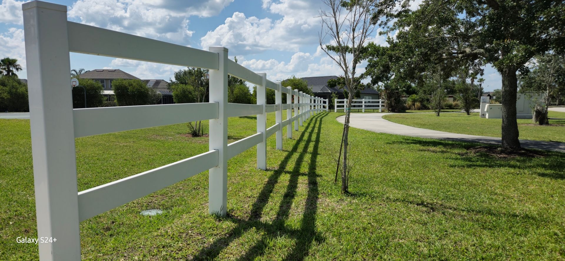 A white fence is sitting in the middle of a lush green field.