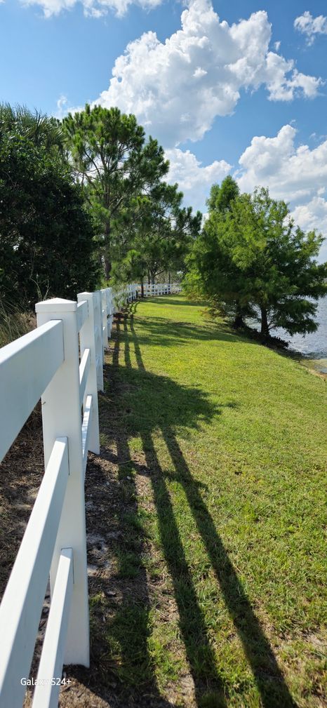 A white fence surrounds a lush green field.