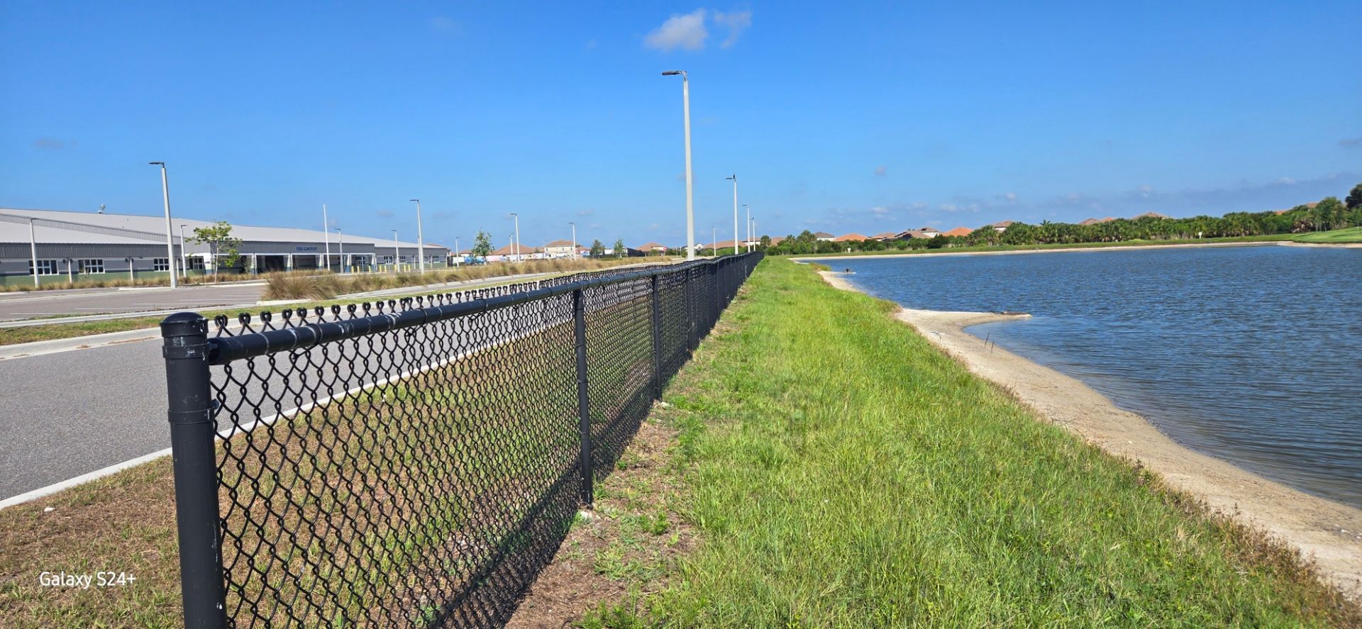 A chain link fence along a body of water.