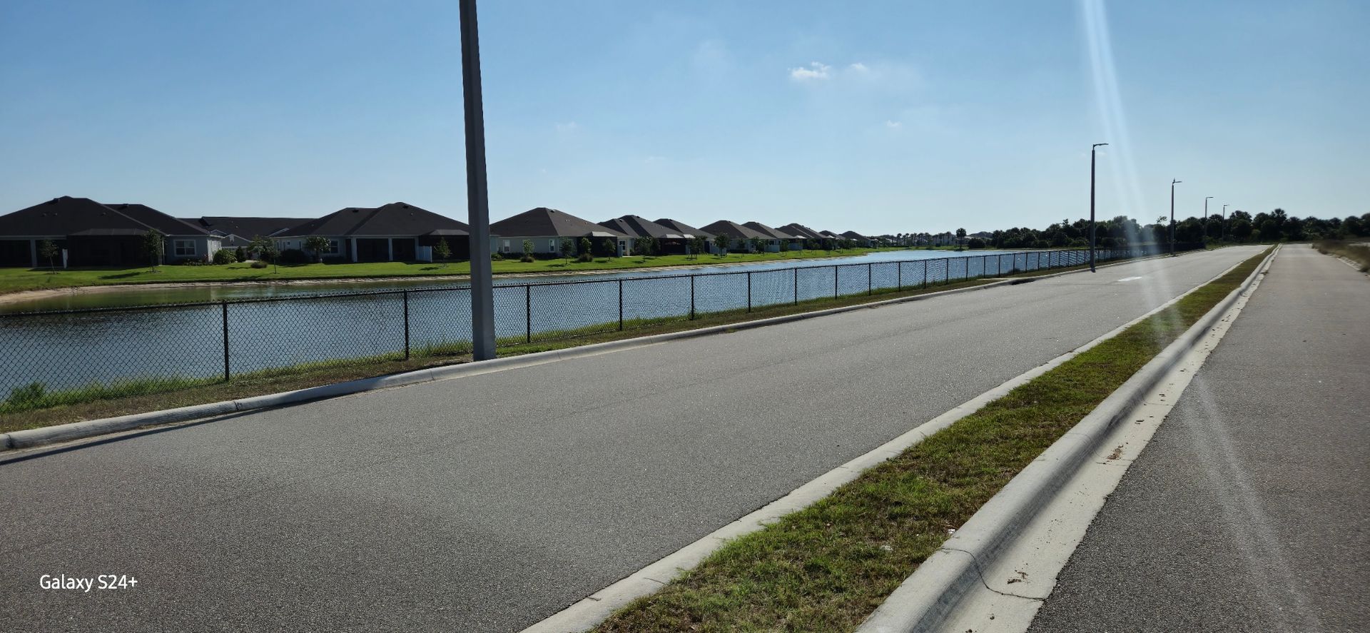 A road with a fence and a lake in the background