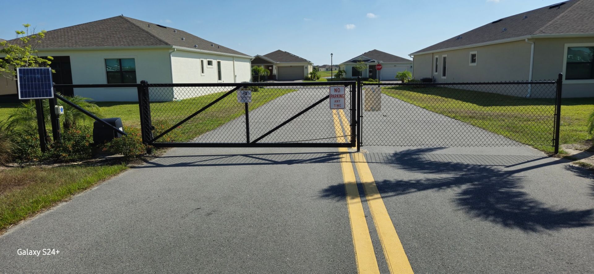 A chain link fence is blocking the entrance to a residential area.
