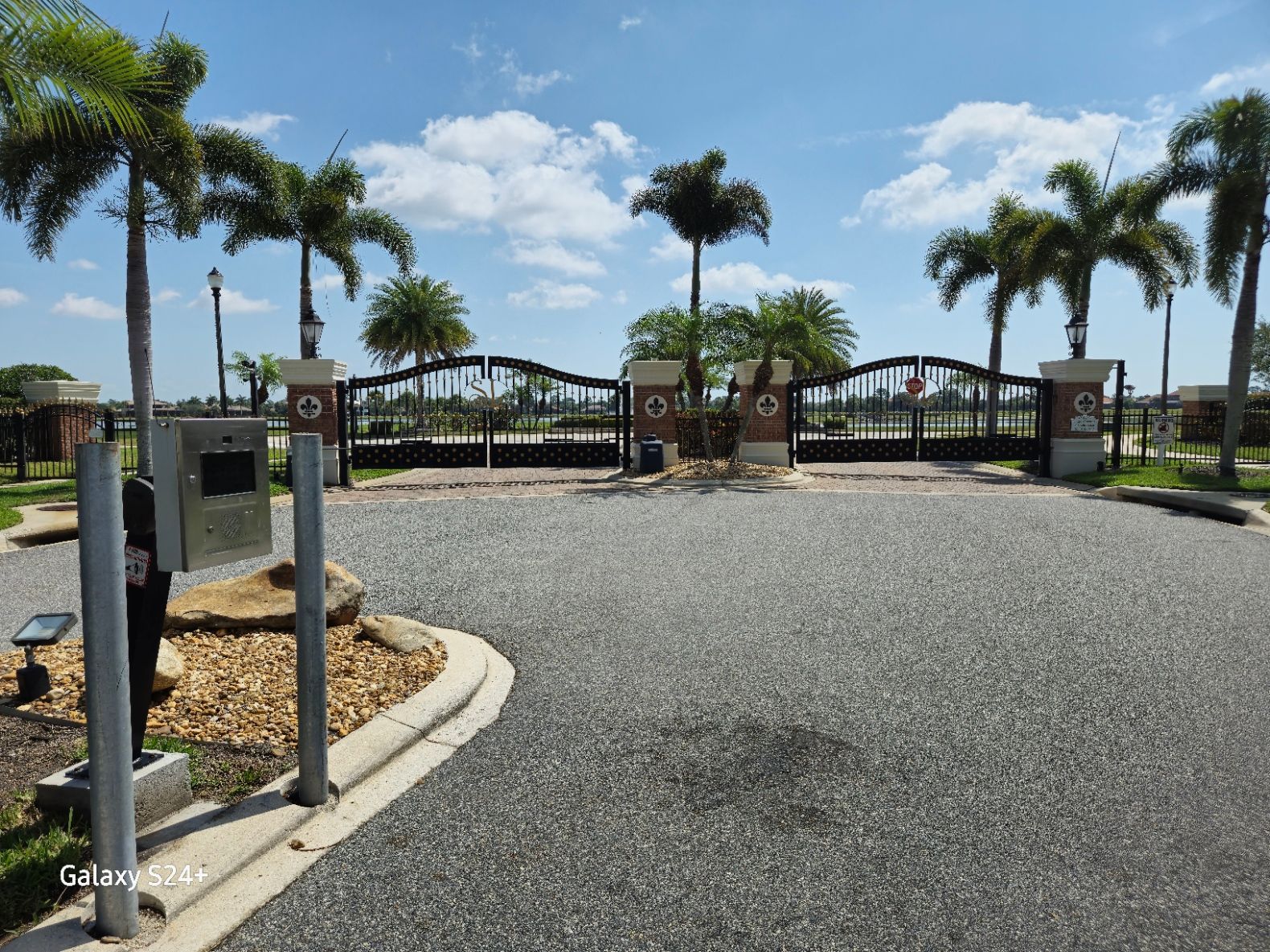 A gated entrance to a residential area with palm trees.