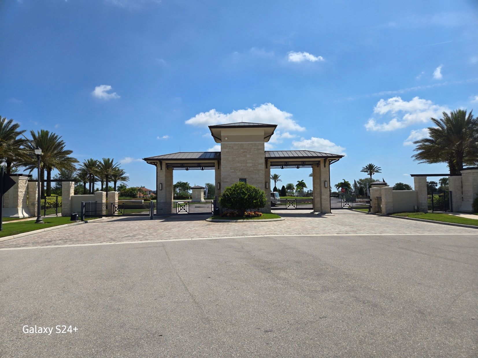 A gated entrance to a residential area with palm trees.