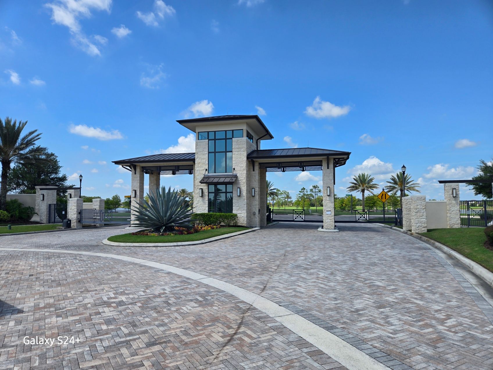 A gated entrance to a residential area with palm trees in the background