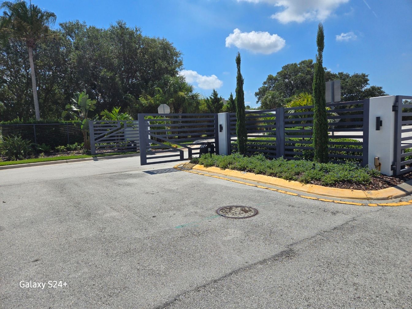A gated entrance to a residential area with trees in the background.
