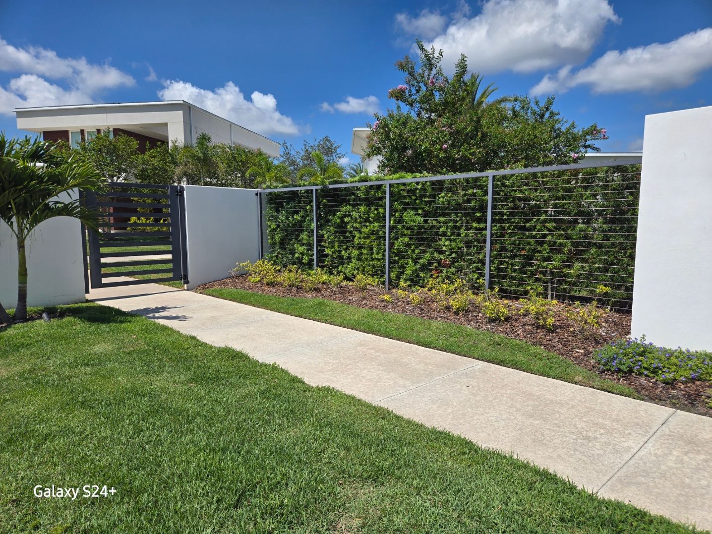 A walkway leading to a house with a fence and a gate.