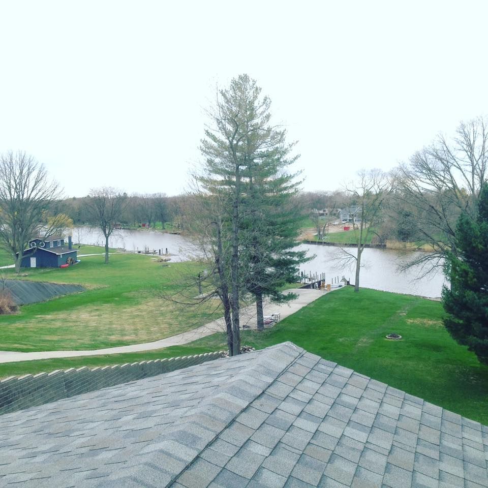 View from a rooftop over a park with a river, grassy lawn, trees, and paths on an overcast day
