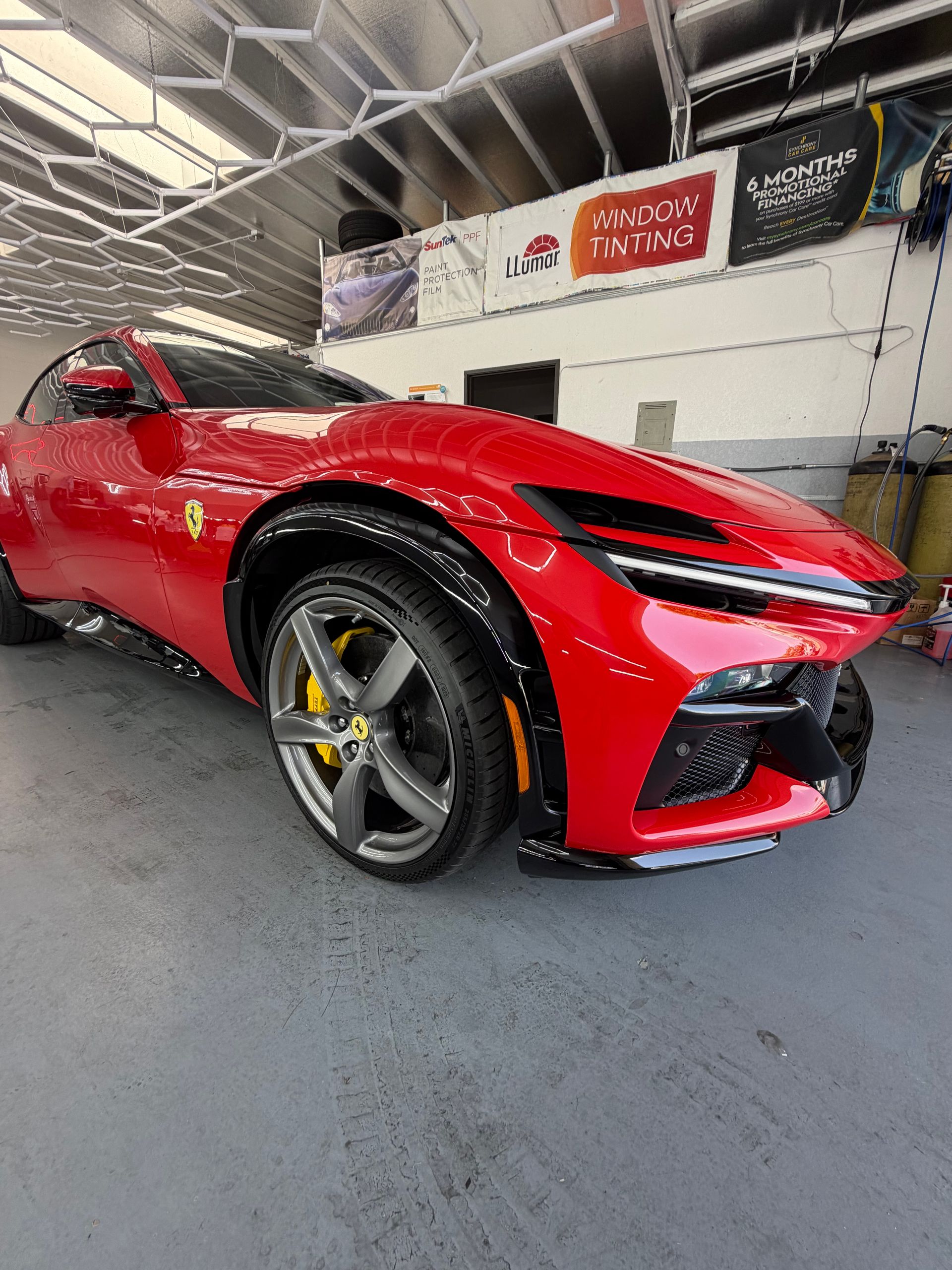 Red sports car parked in a garage, shown from the front-left side.