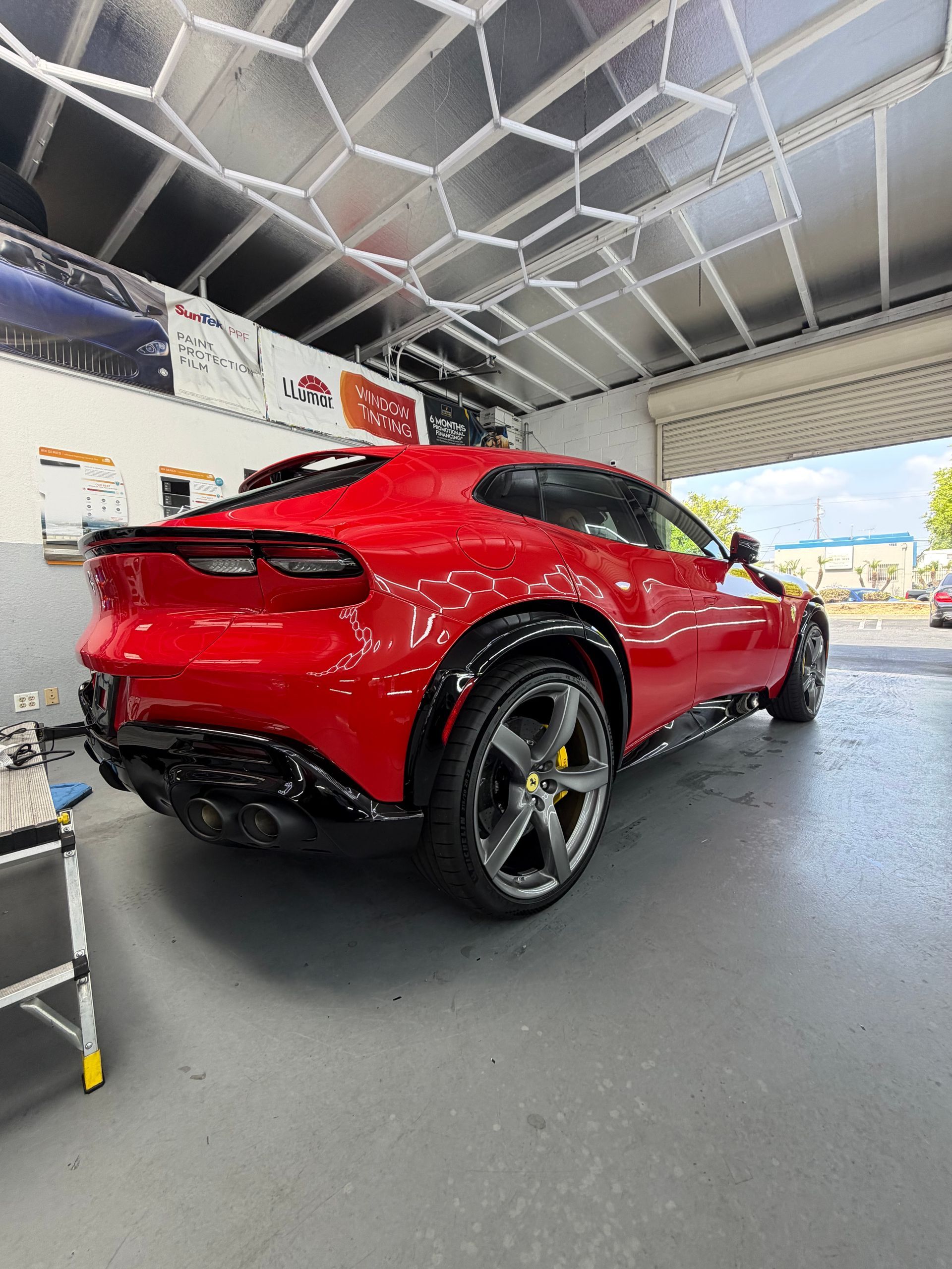 Red sports SUV in a garage, rear three-quarter view with glossy black wheels and a curved roofline.