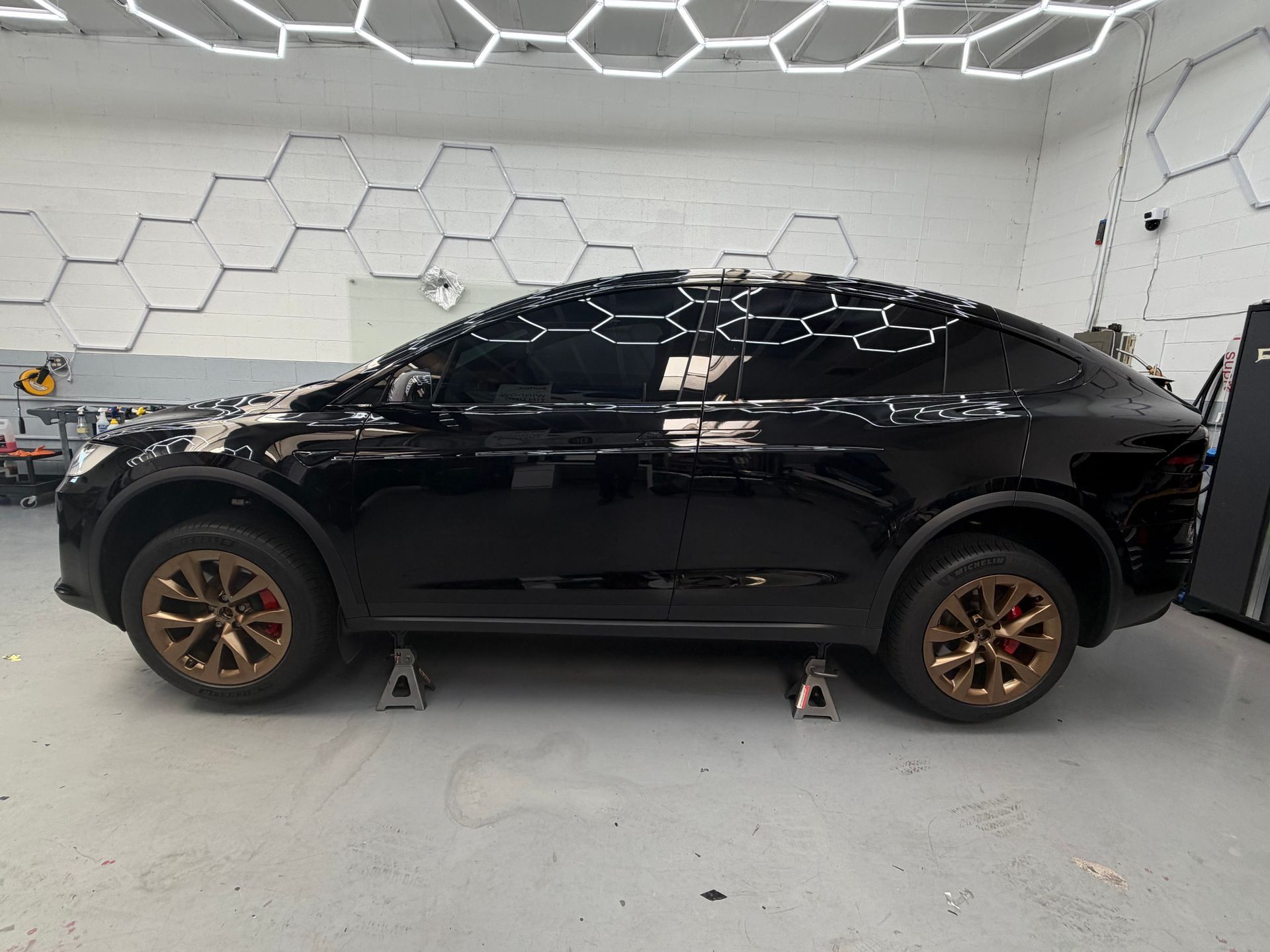 Black SUV in a white photo studio, side view, with bronze wheels.