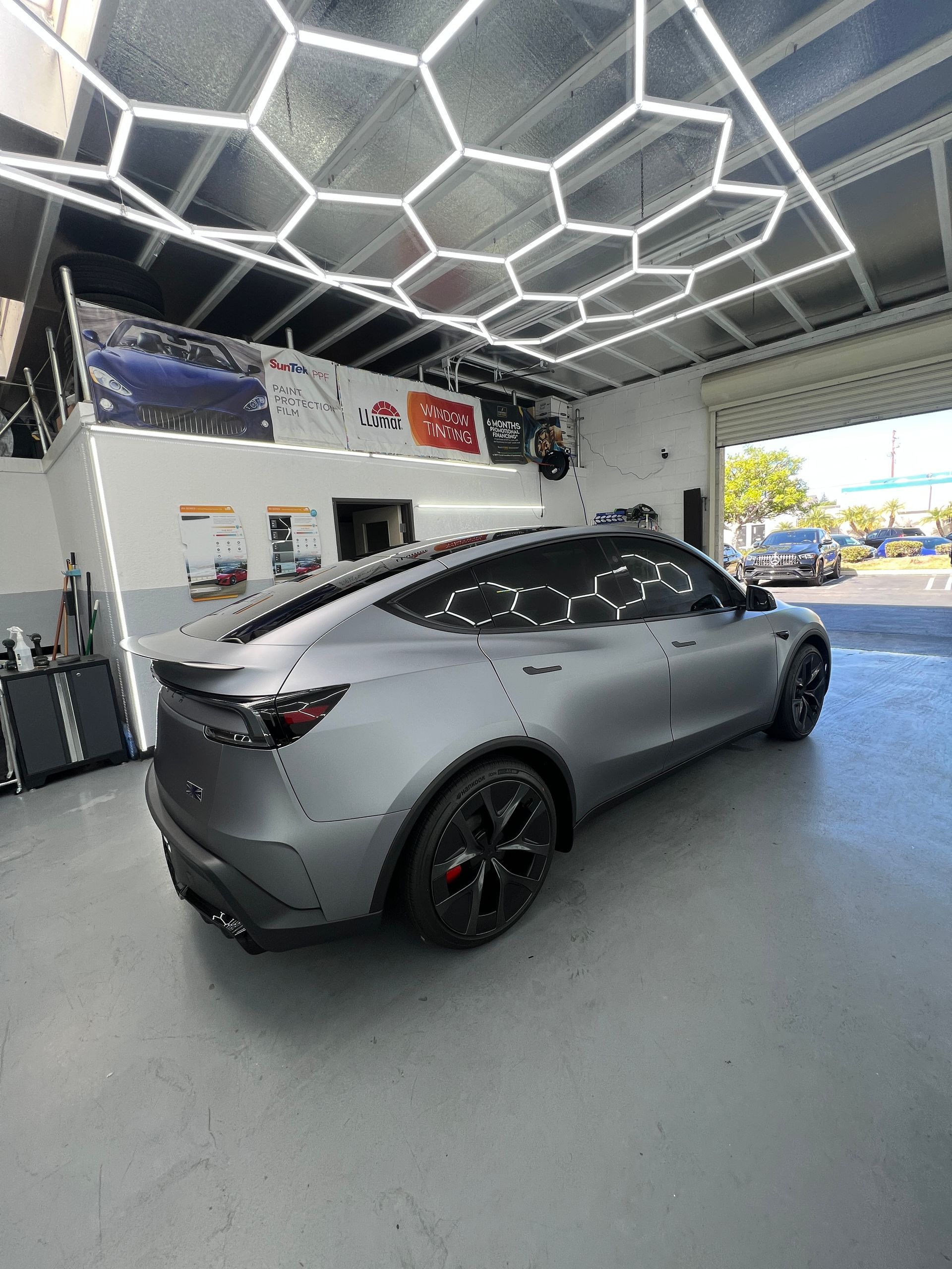 Gray sports sedan displayed in a modern showroom with hexagonal ceiling lights