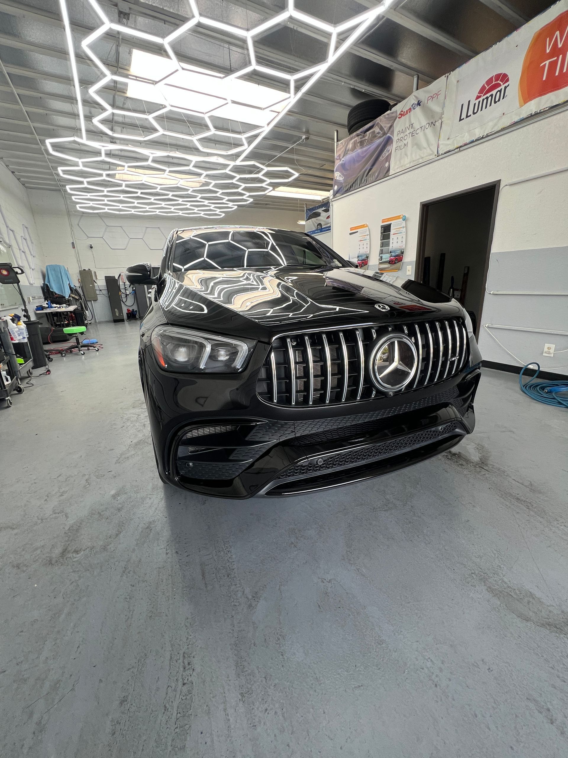 Black Mercedes SUV in a showroom with geometric ceiling lights and a glossy floor