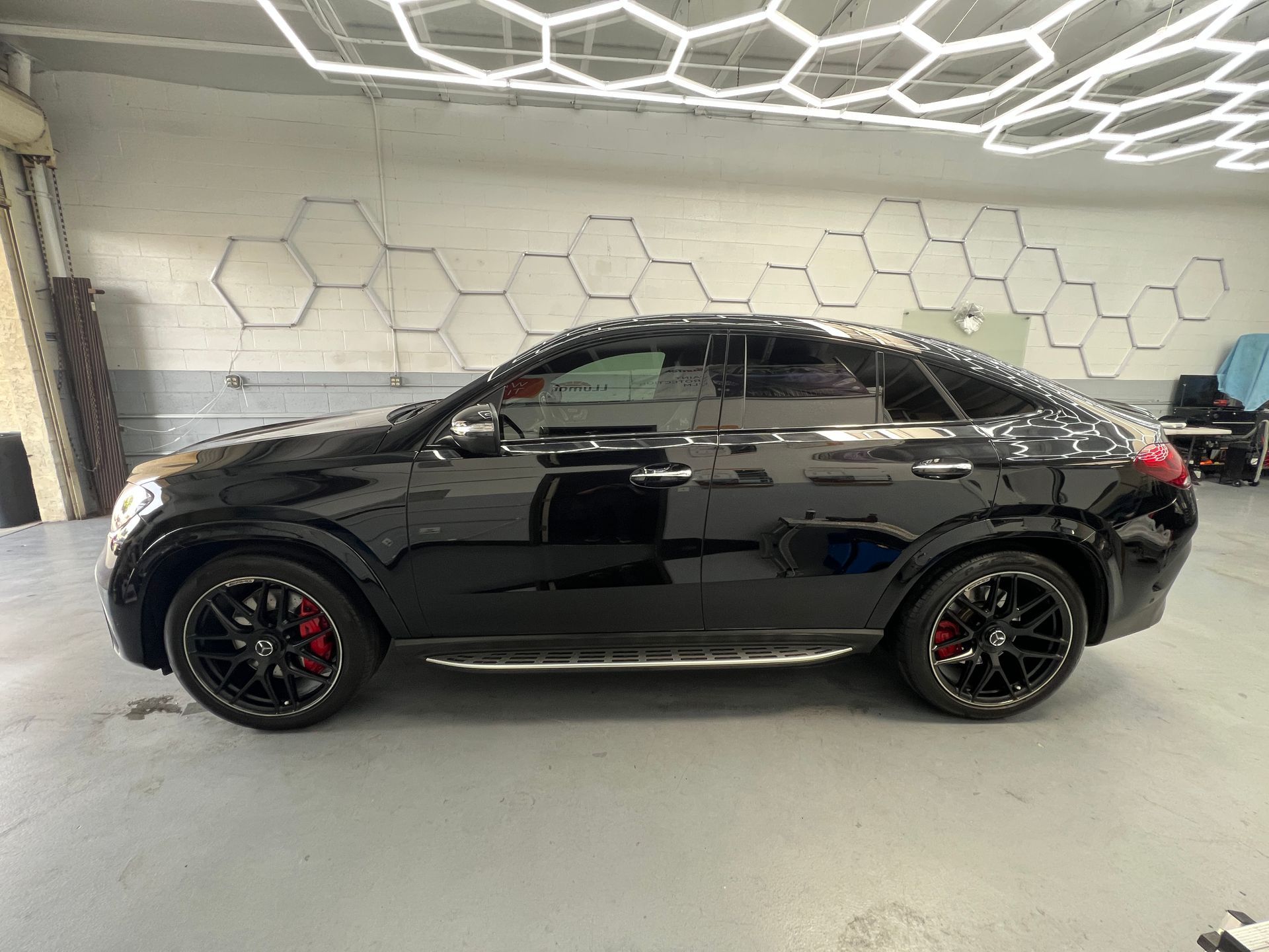 Black sedan in a showroom with hexagonal wall decor and honeycomb ceiling lights