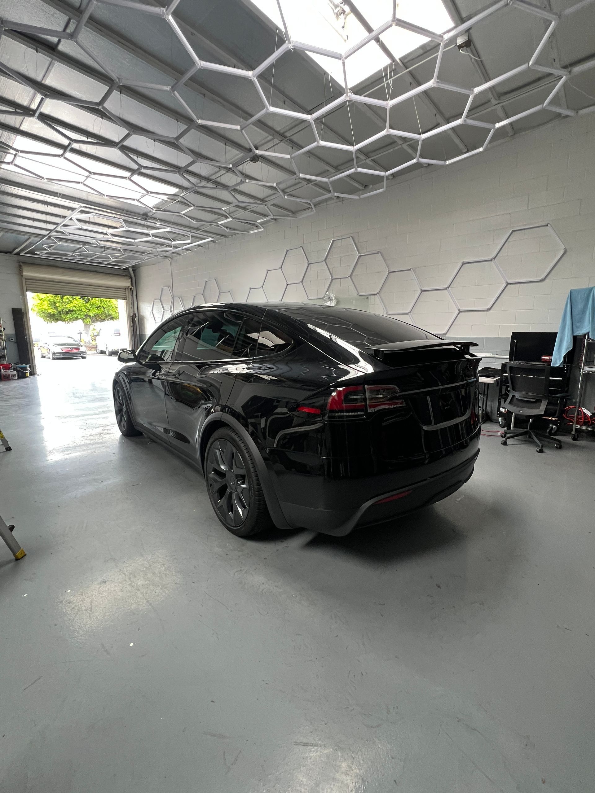 Black SUV in a modern garage with hexagonal ceiling lights and geometric wall panels.