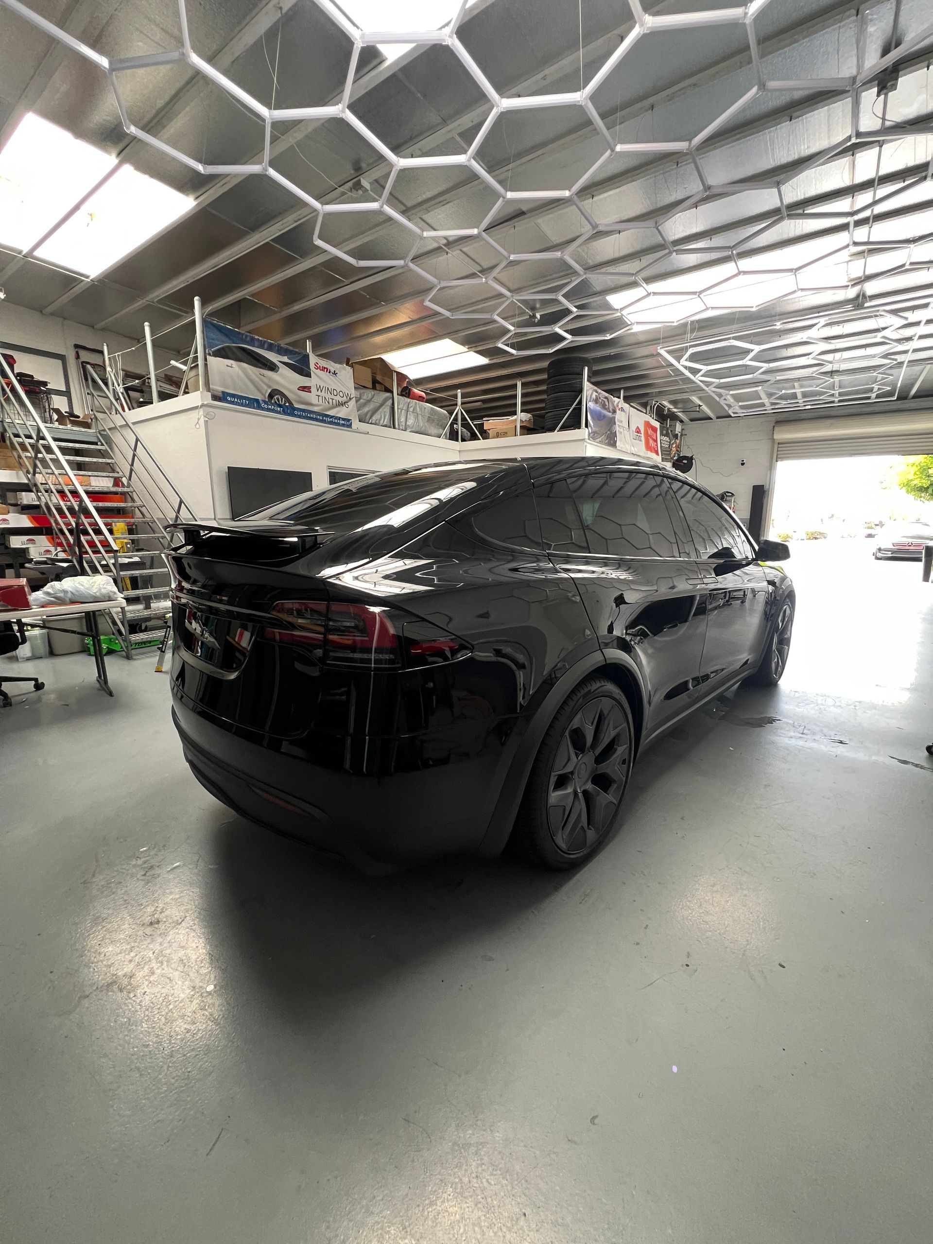 Black SUV parked inside a modern garage with a hexagonal ceiling light pattern